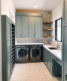 a washer and dryer are in the middle of a kitchen with gray cabinets