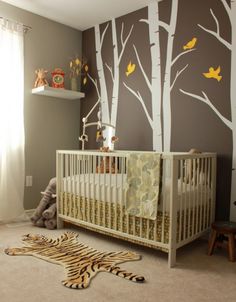 a baby's room decorated in brown and white with trees painted on the wall