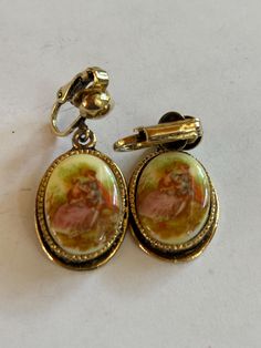 Vintage Goldtoned Clipon Earrings with old Courting Scene measuring 1x3/4" Antique Clip-on Earrings For Anniversary, Antique Round Earrings With Screw Back, Vintage Oval Hallmarked Earrings, Vintage Oval Earrings Hallmarked, Antique Metal Earrings With Vintage Charm, Vintage Brass Clip-on Earrings, Vintage Gold Oval Earrings, Collectible Victorian Oval Earrings, Collectible Vintage Dangle Earrings