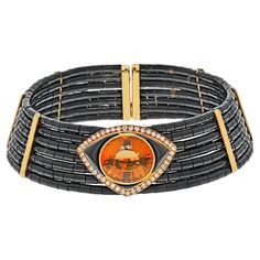 The 18k yellow gold choker is a beautiful and timeless piece of jewelry. Its dramatic style and luxurious design make it a perfect piece to add to any collection. Very unusual this elegant estate choker is a perfect piece for someone who has a long neck. Made of seven rows of cut black onyx circular bars mounted on strings enhanced with a large orange citrine in the center that is further decorated with round cut diamonds set in 18k yellow gold. Neck circumference 14.5 to 15 inches. Comfortable Luxury Yellow Gold Formal Choker, Luxury Elegant Yellow Gold Choker, Luxury Formal Choker With 17 Jewels, Formal Luxury Choker With 17 Jewels, Luxury Yellow Gold Choker, Luxury Yellow Gold Choker For Formal Events, Orange Citrine, Diamond Choker Necklace, Big Necklace