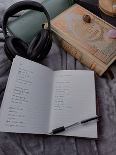 an open book and headphones on top of a bed next to a pair of headphones