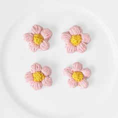 four pink flowers on a white plate with one yellow flower in the middle and three petals attached to each other