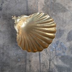 a gold shell shaped dish sitting on top of a table