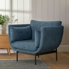 a blue chair sitting on top of a wooden floor next to a potted plant