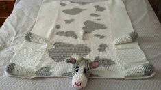 a crocheted cow blanket laying on top of a bed