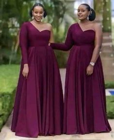 two women in long purple dresses standing next to each other and smiling at the camera