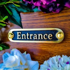 a wooden table topped with flowers and a sign that says entrance on it's side