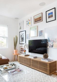 a living room with pictures on the wall and a television in the corner near a couch