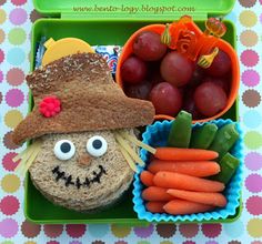 a lunch box with some food in it, including carrots and grapes on the side