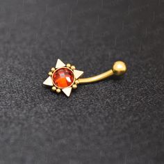 a gold nose piercing with an orange stone