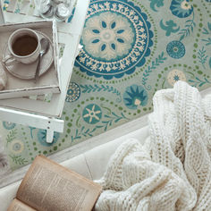 an open book on a couch next to a cup of coffee and a teapot