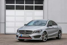 a silver mercedes cla parked in front of a garage