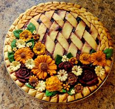 a pie is decorated with flowers and leaves