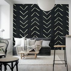 a living room with black and white wallpaper in the corner, two stools on either side