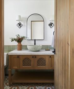 a bathroom with a sink, mirror and wooden cabinetry in it's center