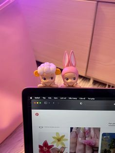 an open laptop computer sitting on top of a wooden table next to two small figurines