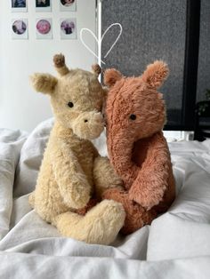 two stuffed animals sitting on top of a bed