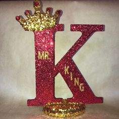 the letter k is made up of glitter and has a crown on top of it