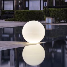 a white ball sitting on top of a pool next to tall buildings and palm trees