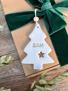 a white christmas tree ornament hanging from a green ribbon on top of a brown box