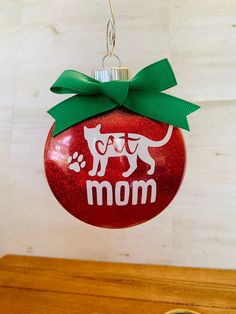 a red ornament with a dog's mom on it and a green bow