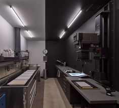 an industrial kitchen with stainless steel appliances and counter tops, along with lights above the counters