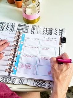 a woman is writing in her planner on the table