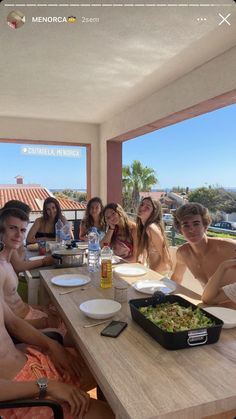 a group of people sitting at a table with food and drinks in front of them