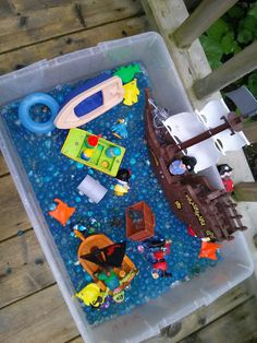 a plastic container filled with toys on top of a wooden deck