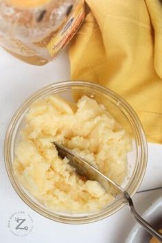 a bowl of mashed potatoes with a spoon in it next to a jar of mustard