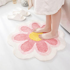 a woman standing on top of a pink and yellow flower shaped rug next to white shoes