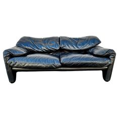 a black leather couch with two pillows on it's back and the seat upholstered