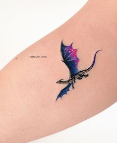 a small tattoo on the arm of a woman with a dragon and stars in it