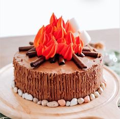 a chocolate cake with frosting and orange flowers on top, sitting on a wooden platter