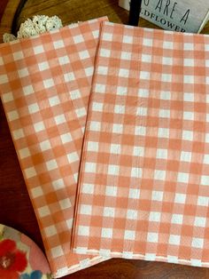 two orange and white checkered napkins sitting on top of a table