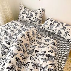 a bed with butterflies printed on it in a white and black color scheme, next to a window