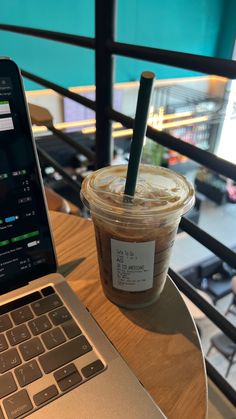 a cup of coffee next to a laptop on a table