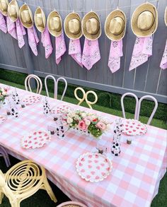 a table set up with pink and white checkered cloths, gold plates and matching hats