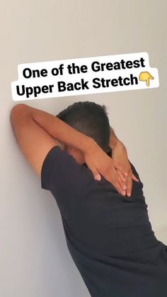 a man leaning against a wall with his back turned to the camera and holding onto a sign that says, one of the greatest upper back stretch