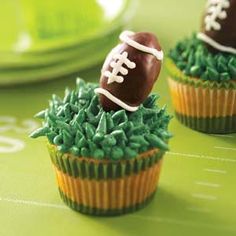 two cupcakes decorated with green frosting and football decorations on top of each other