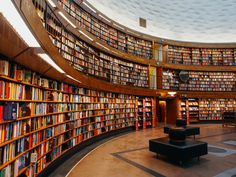 a library filled with lots of books under a circular skylight in the middle of a room