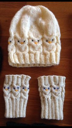 three knitted hats and two mittens sitting on top of a wooden table