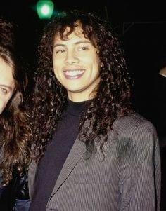 two people standing next to each other in front of a green light and one person with long curly hair