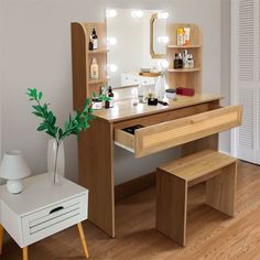 a dressing table with stools and a mirror in the corner, next to a potted plant