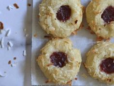 four cookies with jam on them sitting on a piece of paper