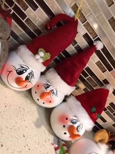 three snowmen wearing santa hats are lined up on the counter in front of a tiled wall