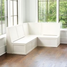 a white bench sitting in the middle of a living room next to two large windows