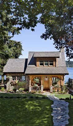 a small wooden house sitting on top of a lush green field next to a lake