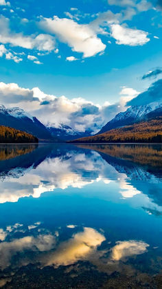 a lake surrounded by mountains under a cloudy blue sky