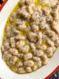 a white plate topped with dumplings covered in gravy next to a fork